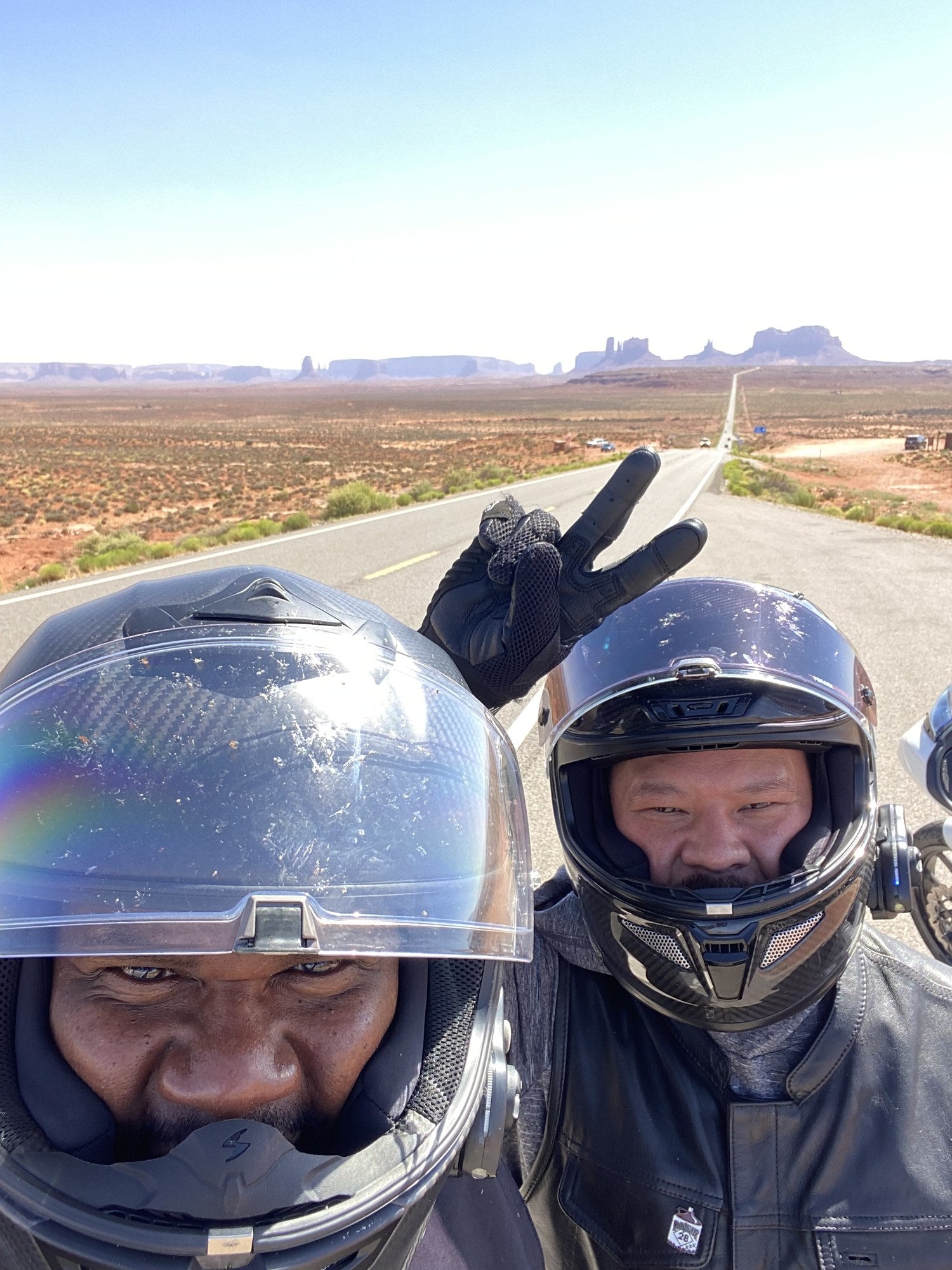 Two KLEENMOTO riders on a desert road in helmets